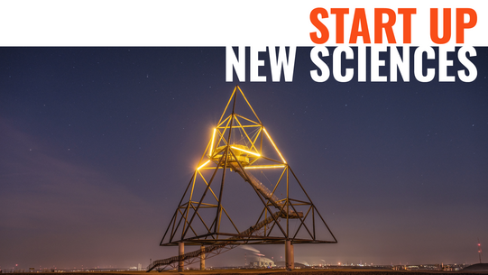 Tetrahedron sculpture illuminated at night in the upper third.