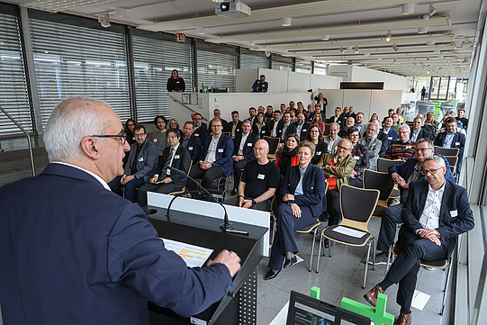Photo: A person speaks at a podium in front of a seated audience.