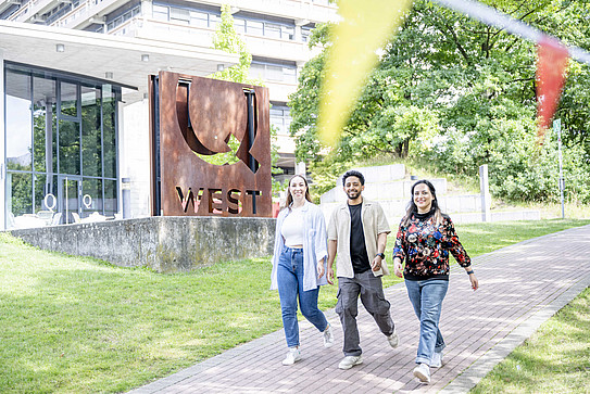 Three people walk across the RUB campus.