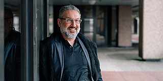 Portrait of a smiling man leaning against a wall.