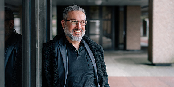 Portrait of a smiling man leaning against a wall.