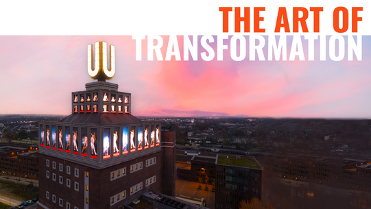 The top of the Dortmunder U with video installation, red-colored sky, Dortmund city center in the background at dusk, and the words “The Art of Transformation” above.