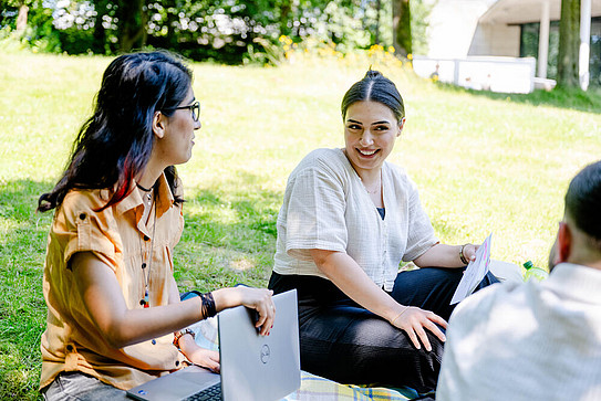 International students sitting on a lawn on the RUB campus