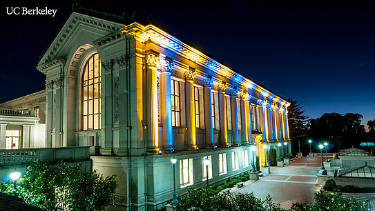 Historic UC Berkeley building illuminated in blue and yellow