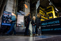 Photo: Several people view exhibition panels in an industrial space.