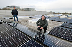Foto: Zwei Mitarbeitende der TU Dortmund präsentieren stolz eine neue Photovoltaik-Anlage auf einem Gebäude der Universität