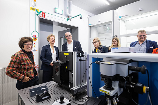 Several people are standing in a laboratory around a table on which various pieces of equipment are placed