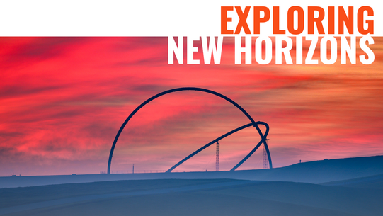 Sculpture consisting of two large semicircles made of steel, photographed against a reddish sky.