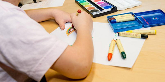Photo of a child that sits at a table and paints.