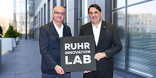 Foto: Prof. Martin Paul, Rektor der Ruhr-Universität Bochum, und Prof. Manfred Bayer, Rektor der TU Dortmund, mit dem Logo des „Ruhr Innovation Lab“.