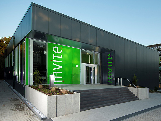 Exterior view of a modern, single-story office building with a striking green entrance area