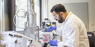 Ein Mann in Schutzkleidung, der in einem Labor Experimente durchführt.