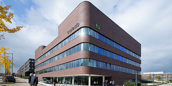 Photo: An exterior view of the CALEDO research building. CALEDO is a brick-style building with large windows and rounded edges.