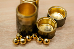 Photo: Golden balls and a golden tin on a wooden surface.