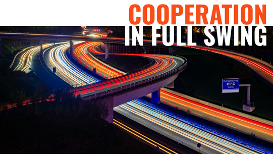 Nighttime photograph of a highway interchange in the Ruhr region; the taillights form red stripes, while the headlights form white stripes.