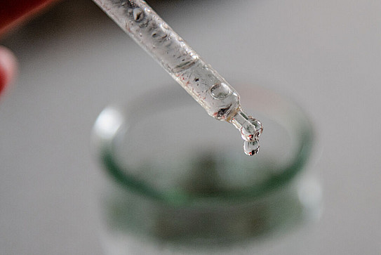 Close-up of a pipette dispensing liquid drop by drop