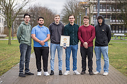 Zu sehen sind fünf Studenten, die in einer Reihe nebeneinander stehen und ihre Erfindung, das "Light Lab Board" in der Hand halten. 