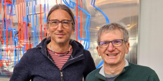 Photo: Prof. Eike Kiltz and Prof. Christoph Paar smile for the camera.