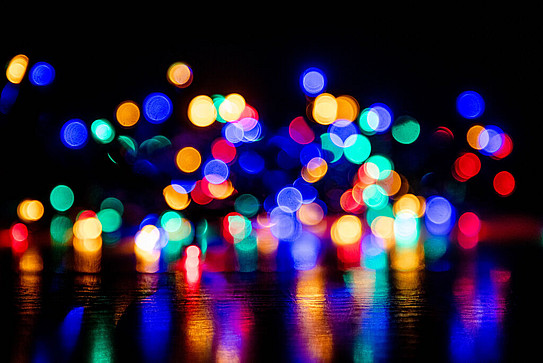 Photo: Colorful dots of light against a dark background.