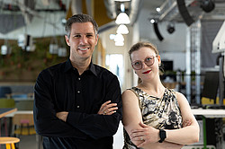 Foto: Ein Mann und eine Frau stehen mit verschränkten Armen in einem Raum.