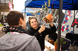 Foto: Auf einem Flohmarkt auf dem Campus der Ruhr Universität Bochum zeigt eine Studierende einem anderen Studierenden einen Blumentopf